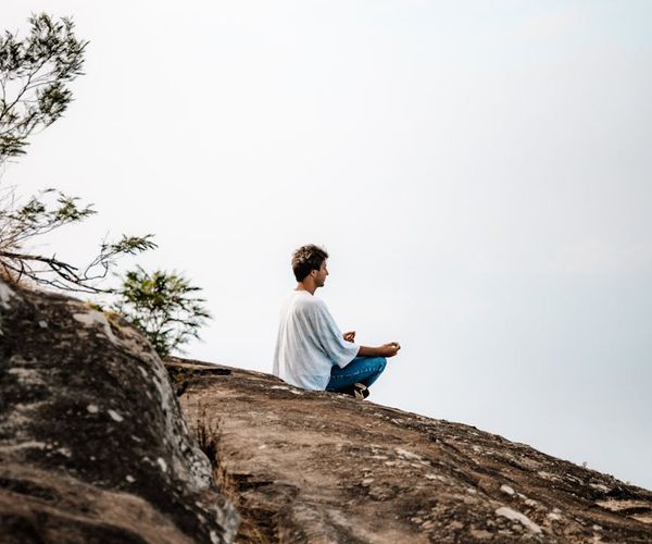 A man meditating outdoors, showing peace and mental clarity.